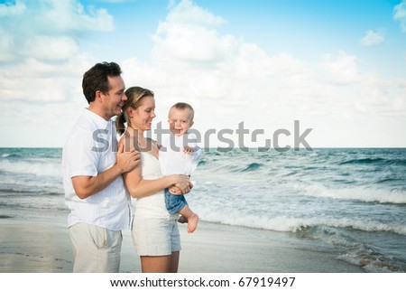 New parents having fun with baby in the sun on the beach