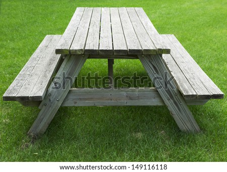 wooden picnic table with benches on a green grass lawn