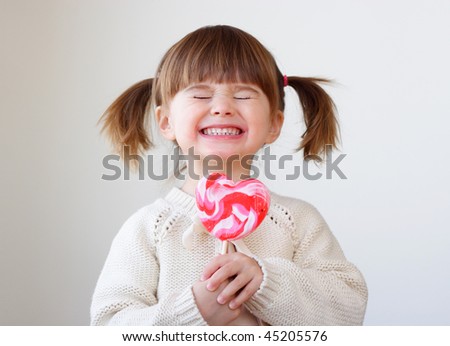 stock photo Beautiful little girl holding a big heart shaped lollipop