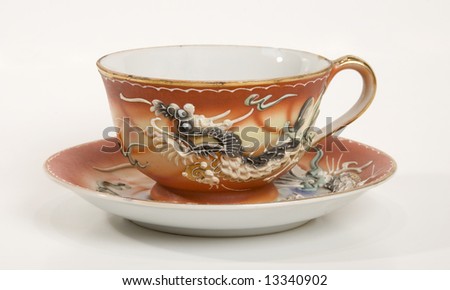 A tea cup with a dragon design and saucer.