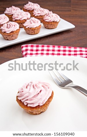 Mini sized pink raspberry cupcakes on a white plate. Home made and gluten free.