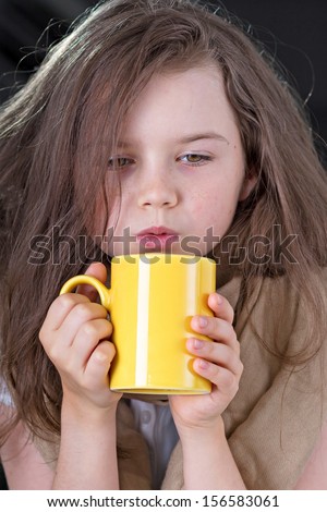 Tired and cold. Cute girl warming up with a cup of hot chocolate or tea