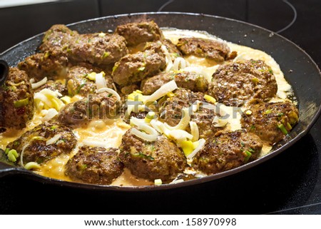 Cooking flat meatballs with zucchini mixed in, in a beautiful forged iron pan. A healthy meal.