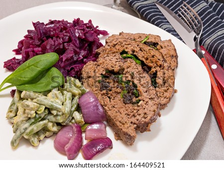 Home cooked meal. Meatloaf filled with spinach and prunes with a side dish of red cabbage and green beans.