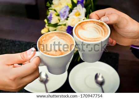 Man and woman\'s hands and coffee cups with hearts