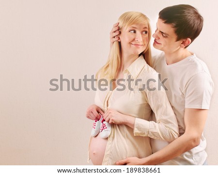 happy smile young pregnant couple expecting a baby with little sneakers family relationship