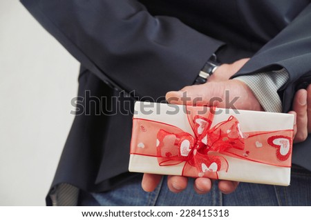 man in suit holding present behind, holiday concept