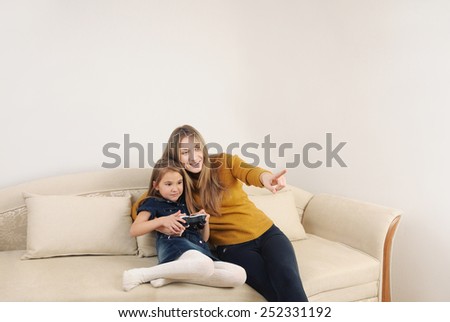 happy mother and daughter relaxing and playing TV games on the sofa at home, happy family concept