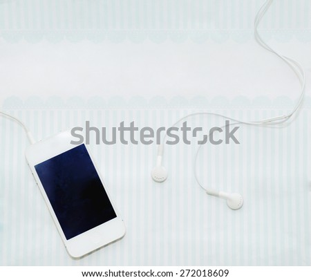 white smart phone with earphones and isolated screen on soft color table, technology concept