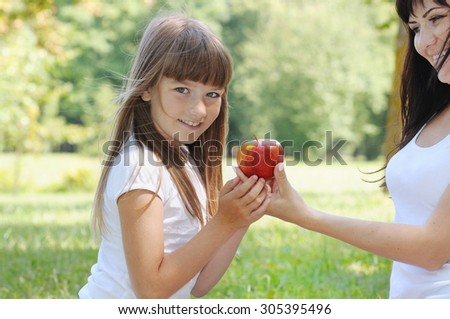 happy girl and her mother having fun on picnic in the park in sunny summer day, happy family concept