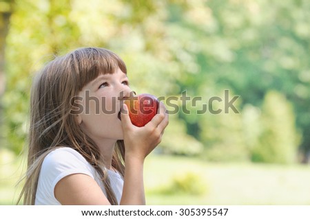 happy girl eating apple on picnic in the park in sunny summer day, happy family concept
