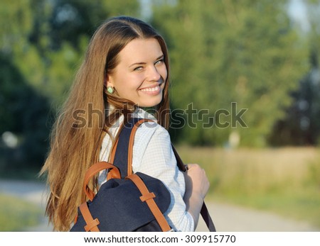 young happy student walking with bag in the park near campus; lifestyle concept