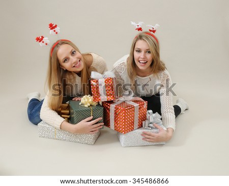 Two happy women hug heap of gift boxes. Christmas and New Year concept. Studio shot on grey background. Christmas spirit.Gift is never too much