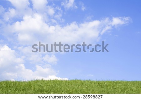 Beautiful green grass against blue sky and clouds representing perfect land.