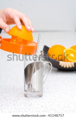 Pouring homemade orange juice in glass on kitchen desk.