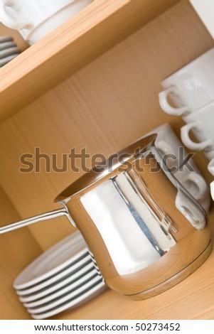 Kitchen-ware in top closet on wooden shelves.