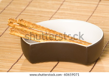 Salty sesame sticks in dish and on table cover.