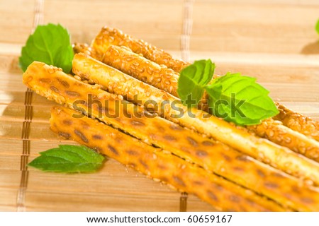 Salty sesame sticks on table cover with mint leaves.