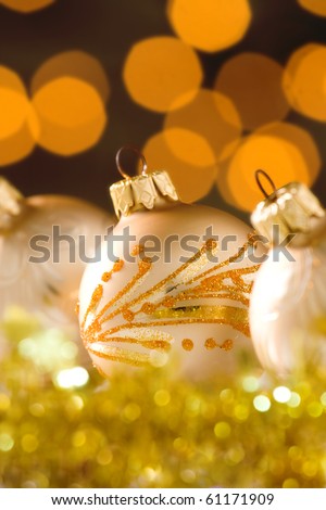 Gold decorated Christmas baubles with small lights out of focus in the background.