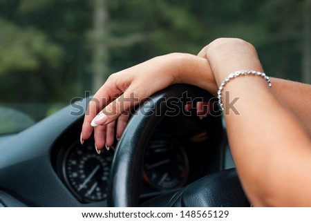 Female hands on steering wheel of a car