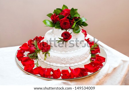 the wedding cake decorated with live red roses