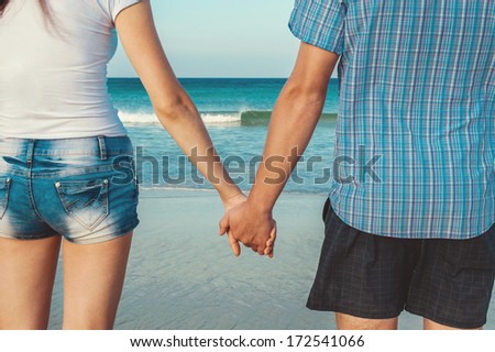 Man and woman holding by hands against the sea