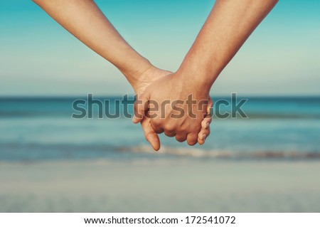 Man And Woman Holding By Hands Against The Sea