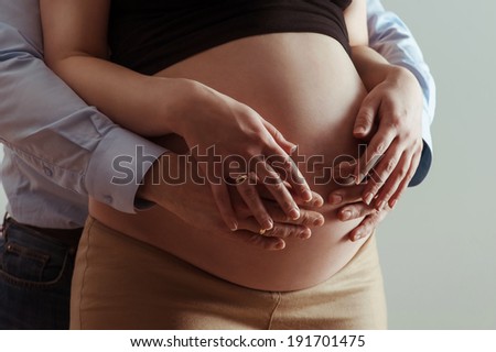 Man's hands embrace a belly of the pregnant woman