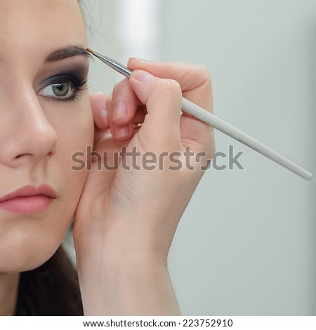 Make-up artist applying eyebrow make-up, close-up, selective focus