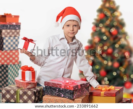 Smiling child in Santa red hat holding Christmas gift in hands. Christmas concept.