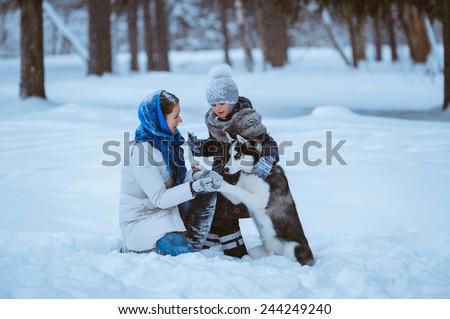 little girl with her mom walking with husky dog in winter forest