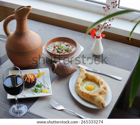 serving table, traditional dish of georgian cuisine, khachapuri, a soup, a jug of wine