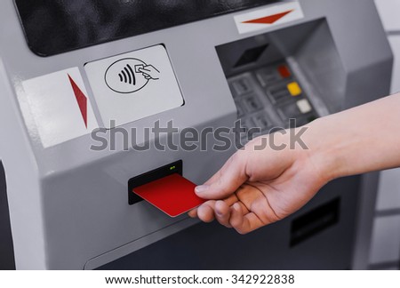 Hand inserting credit card into bank machine to withdraw money