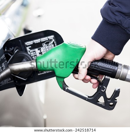 Pumping gas at gas pump. Closeup of man pumping gasoline fuel in car at petrol station
