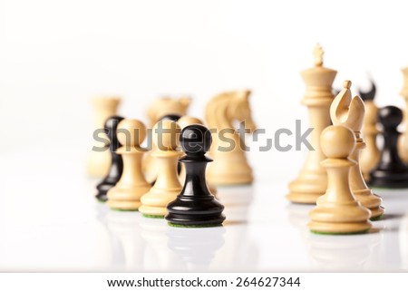 Black and white chess pieces standing on a white glass