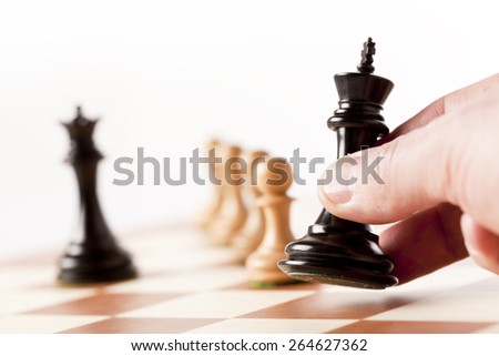 Playing chess - a hand moving the black king on a chessboard
