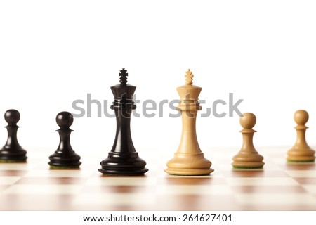 Two armies - black and white chess kings with pawns standing on a chessboard - closeup