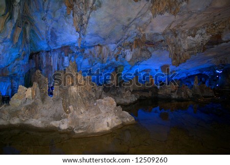 Water-eroded Reed Flute Cave with its stalactites, stone pillars and rock formations created by carbonate deposition, illuminated by colored lighting. Guilin, China.
