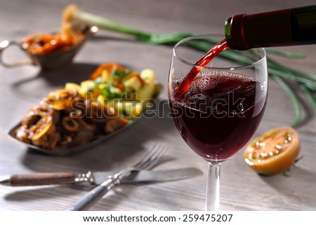 Pouring red wine and food background