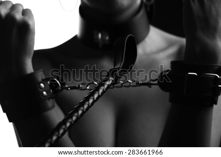 leather whip and a woman in handcuffs, sepia and toning