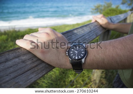 Man wearing watch waits by the beach