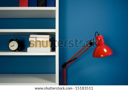 White bookcase with red reading lamp in blue room
