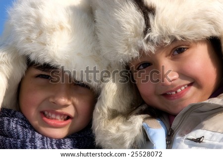 Cute girl and boy winter portrait in the fur-cap