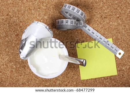 Yellow sticky note to self reminding to lose weight with measuring tape and yogurt