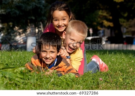 Happy three little friends laying on the grass in the park