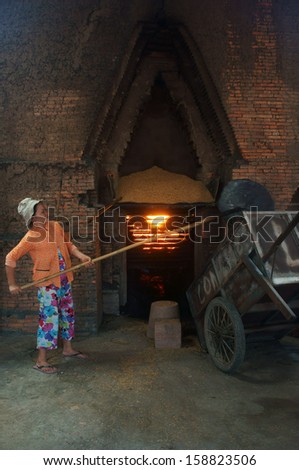 VINH LONG, VIET NAM- JULY 1: Worker  working at brick factory, workwoman shoveling rice husk into oven to make flame in Vinh Long, Viet Nam on July 1, 2013