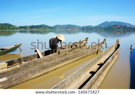 BUON ME THUOT, VIET NAM- FEBRUARY 18: People clean dug out canoe (boat) to transport  for travel in Buon Me Thuot, Viet Nam on February 18, 2013
