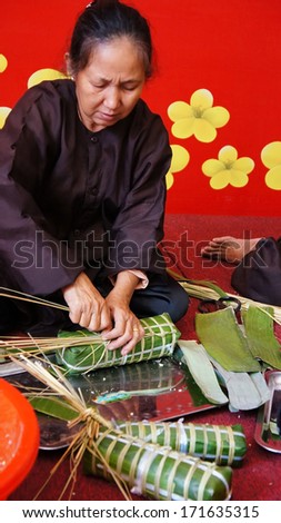 HO CHI MINH CITY, VIET NAM- JAN 15: Senior people make traditional cake for New Year occasion, the cake cover by green bananna leaf in Ho Chi Minh, Vietnam on Jan 15, 2013