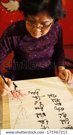 HO CHI MINH CITY, VIET NAM-JAN 15: Woman write calligraphy, she write vietnamese letter at year end event, calligrapher who have kind face, intellectual wear traditional dress, Vietnam, Jan 15, 2013