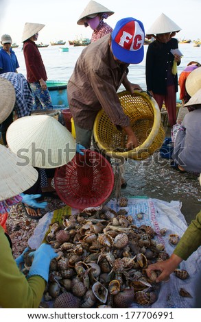 PHAN THIET- VIETNAM- JAN 21:  Seafood market on beach, people trader fishing product in morning, boat on water,  woman buy and sell fresh food, Viet Nam, Jan 21, 2014